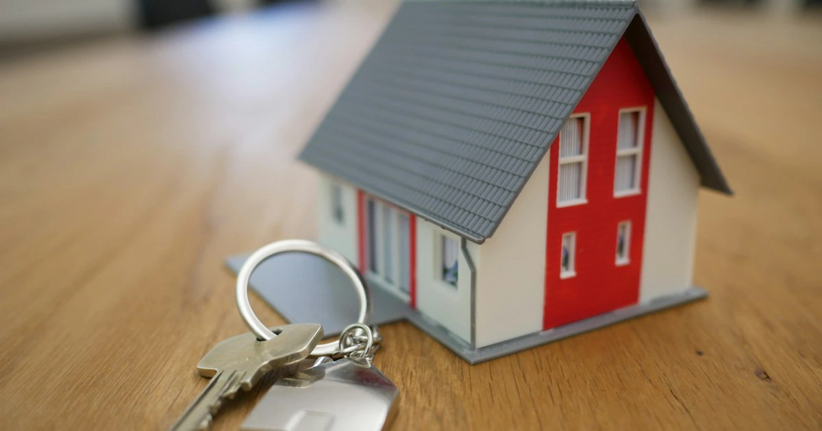 Casa em miniatura e chaves sobre mesa, simbolizando o contrato de locação