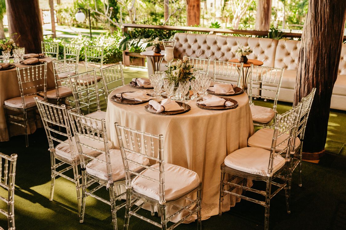 Wedding reception table surrounded by transparent chairs with elegant place settings