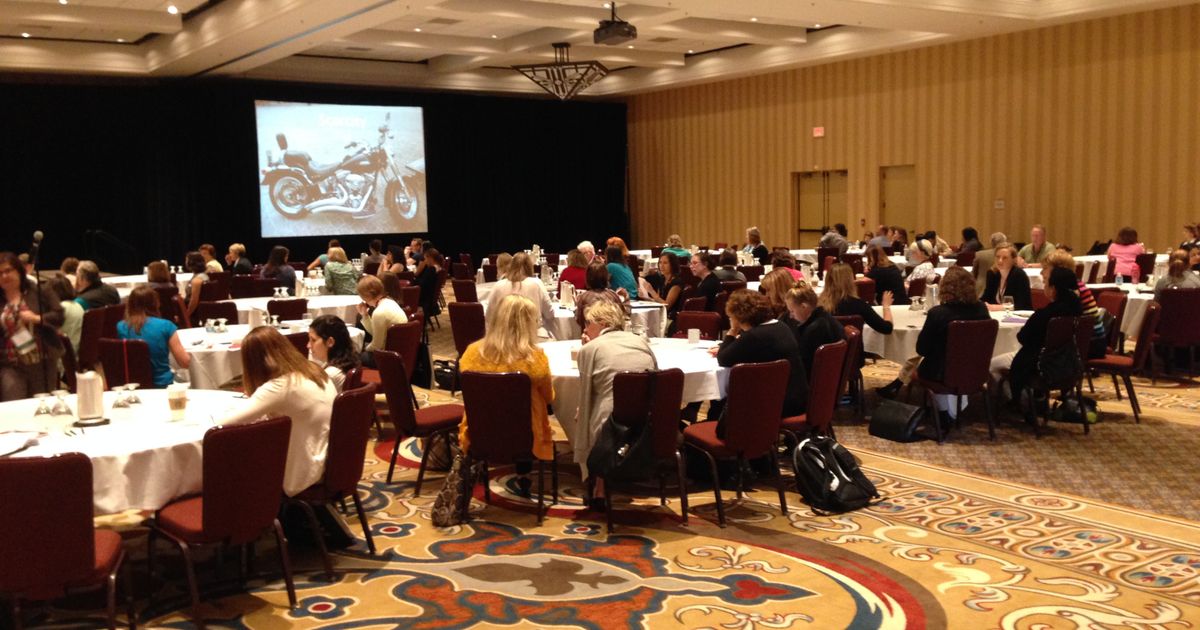 Business professionals gathered at a corporate conference with a presentation screen and microphones