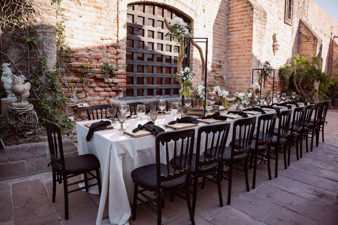 Long wedding reception table with floral centerpieces set under an open sky