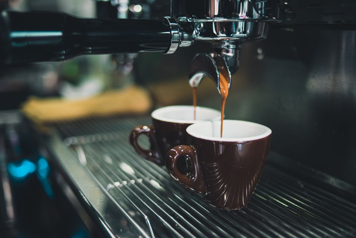 A close-up of espresso brewing from a professional machine into ceramic cups