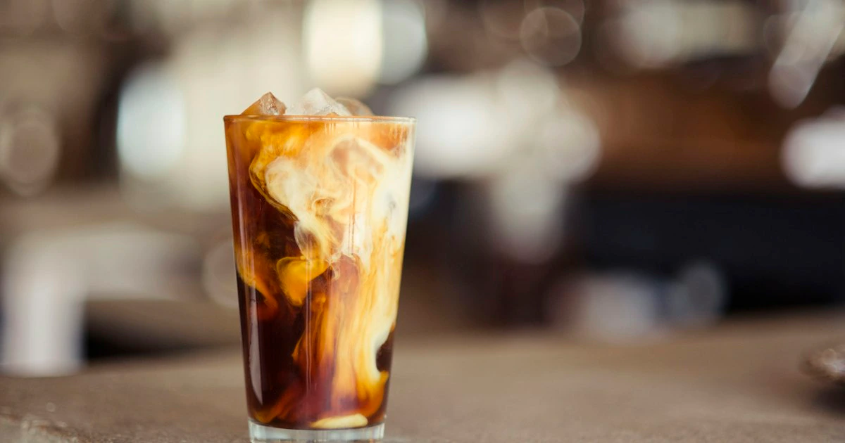 Cold brew coffee in a clear glass jar with ice on a rustic wooden table