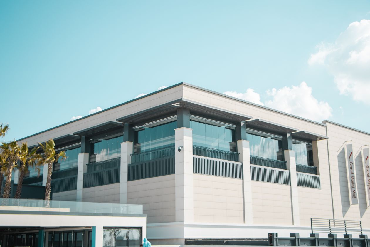 Fachada moderna de centro comercial con estructura de vidrio bajo cielo azul