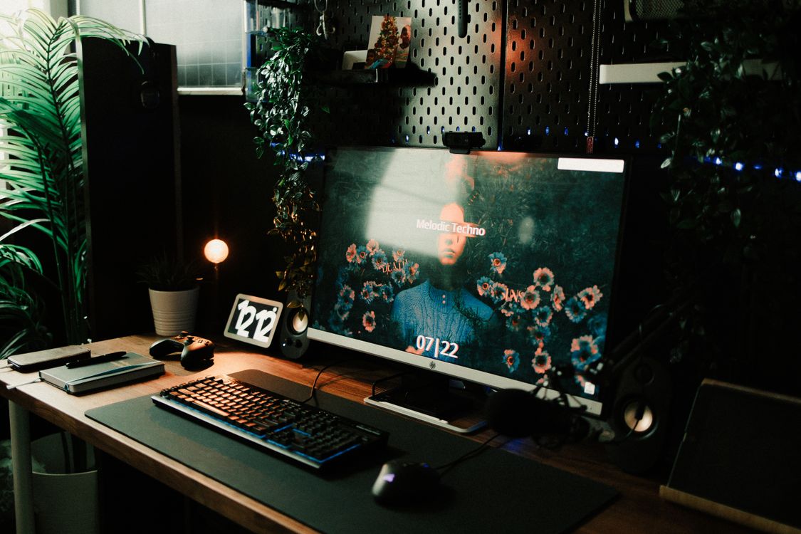 A home office desk setup with a computer monitor, keyboard and indoor plants