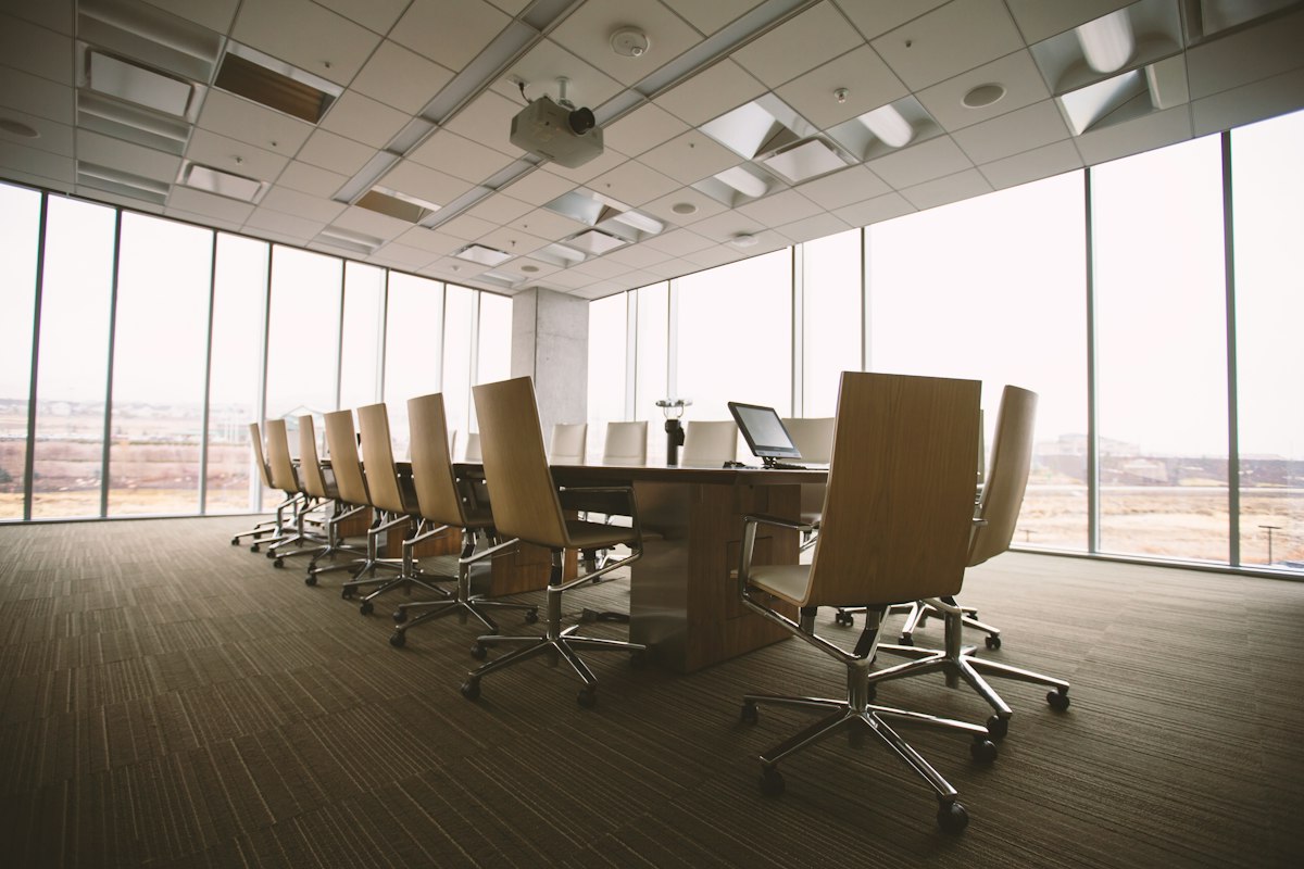 Oval boardroom table surrounded by executive chairs in a bright meeting room