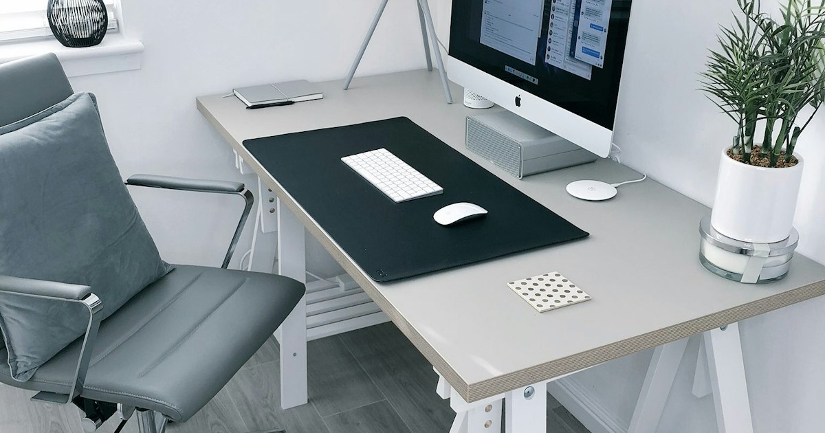 A tidy wooden home office desk with a laptop and small storage