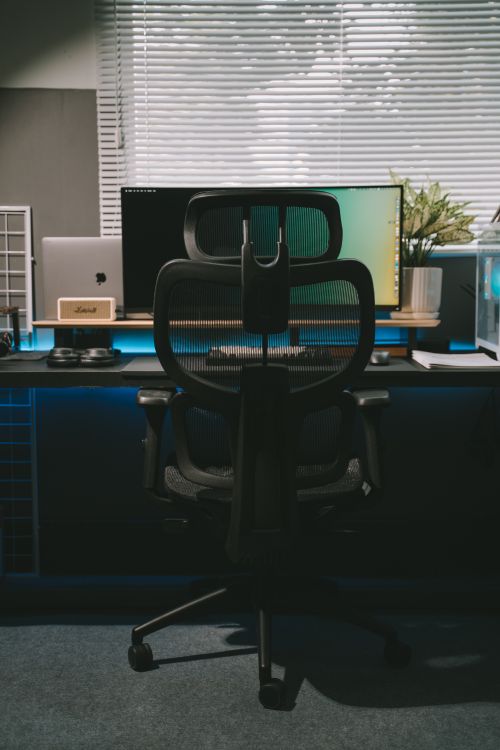 A modern ergonomic desk setup with an adjustable chair and a widescreen monitor