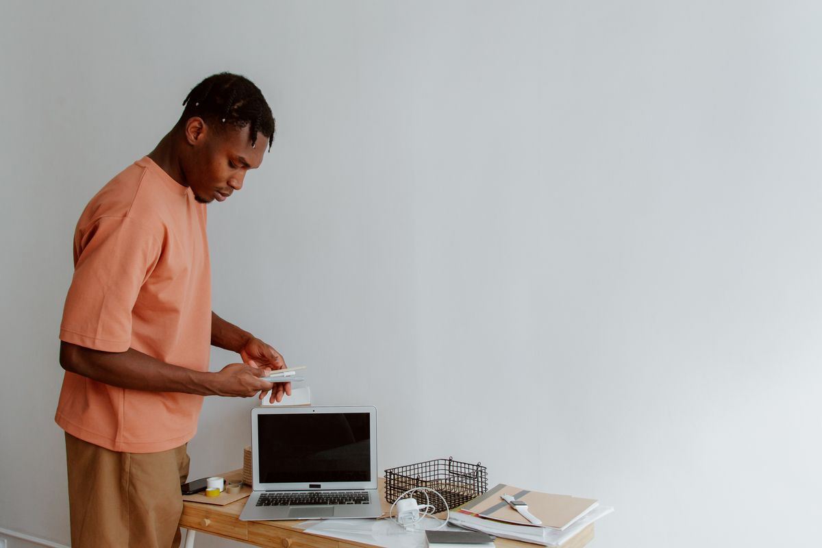 Man organising his workspace at a minimalist office desk with notebooks and a laptop