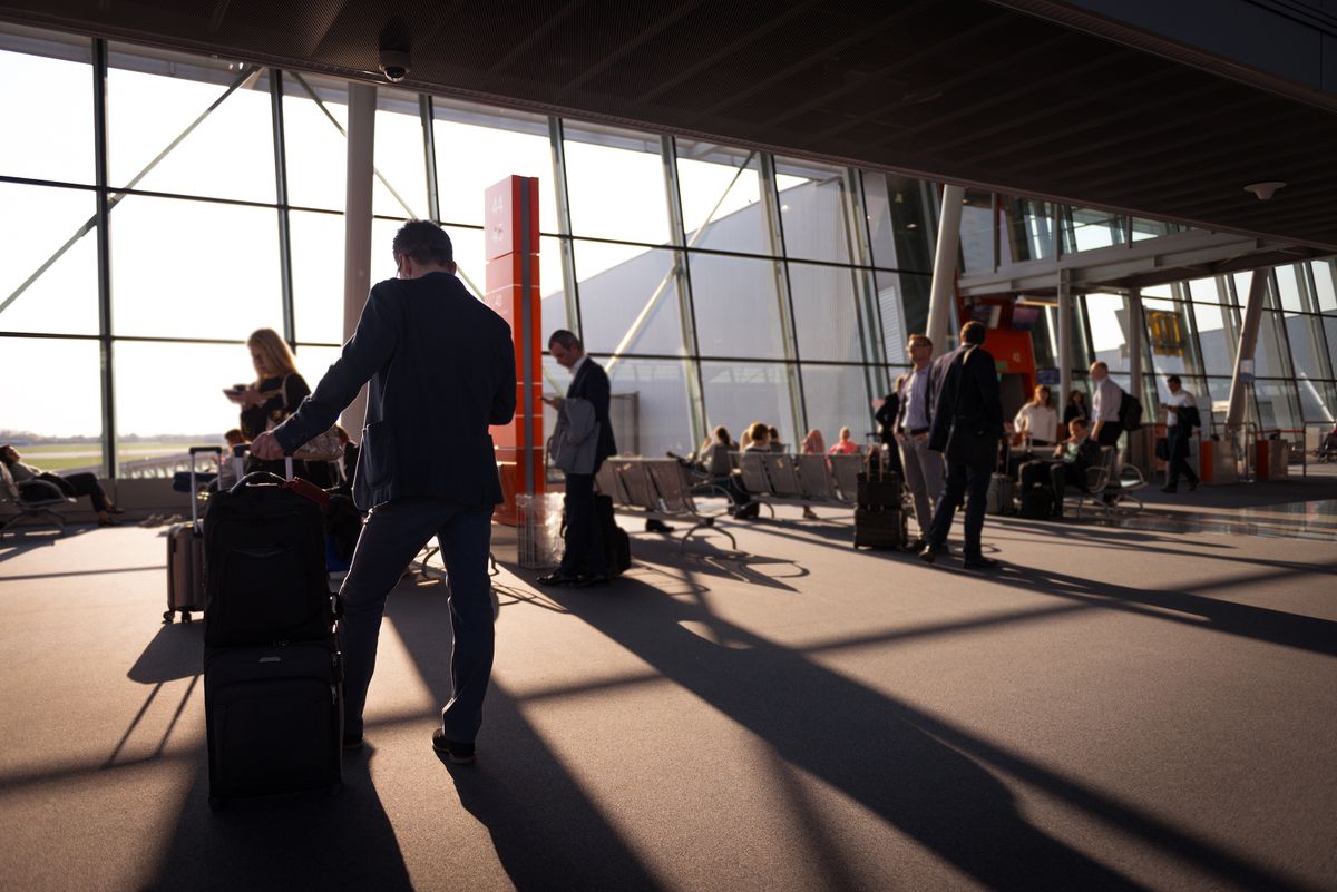 Travelers with luggage in a busy airport terminal arrival area