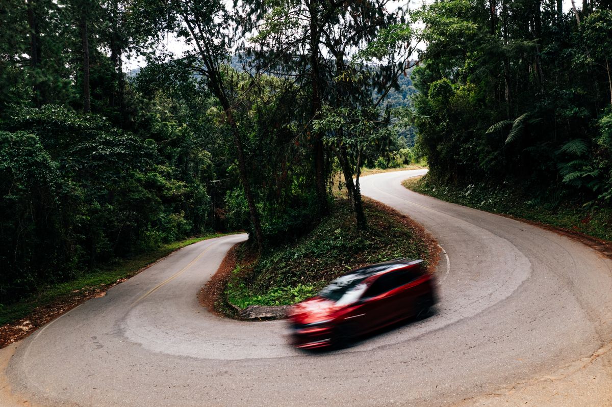 A car driving through a winding, forested mountain road