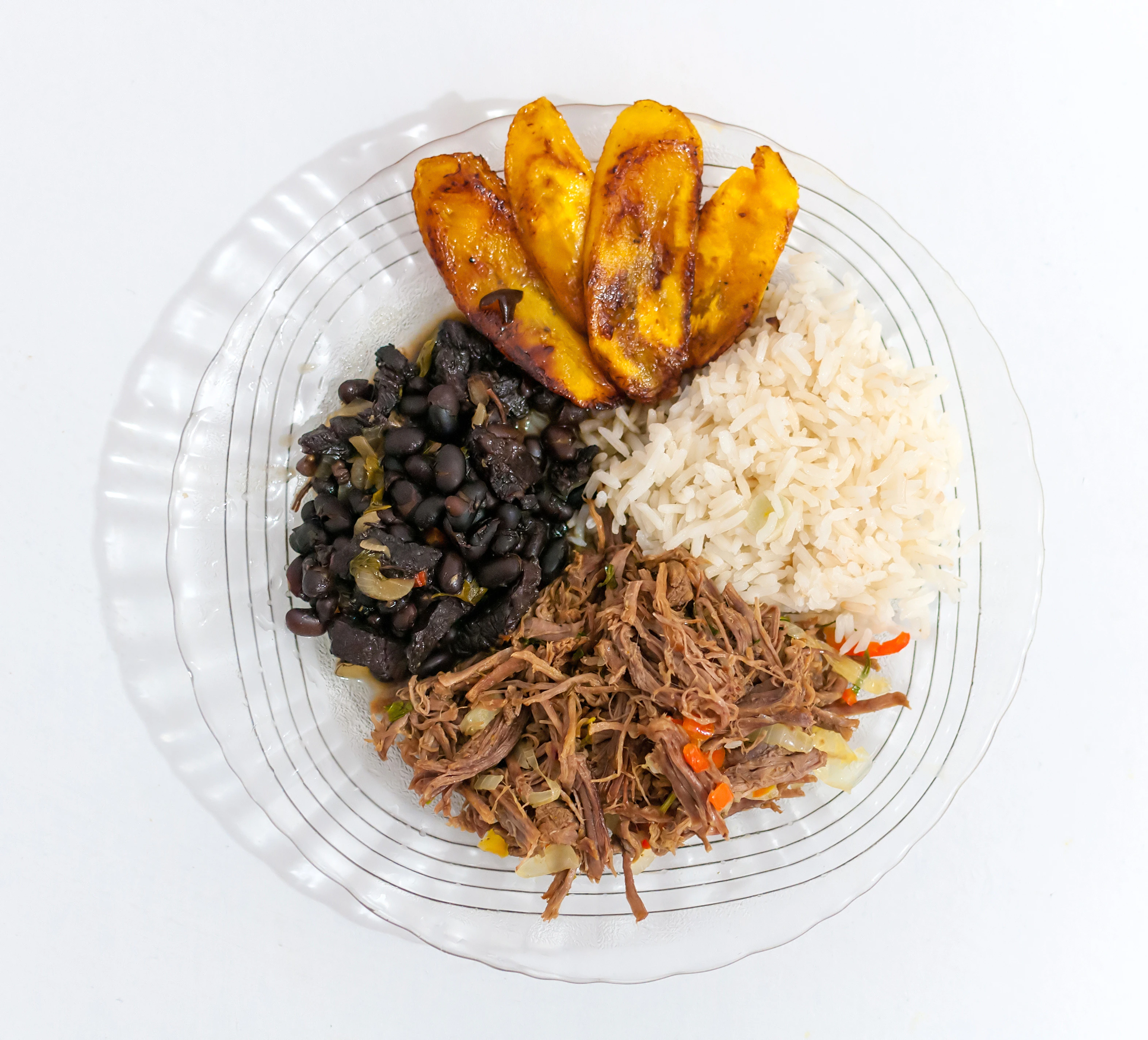 Plato de pabellón criollo venezolano con arroz blanco, carne mechada, caraotas negras y tajadas de plátano