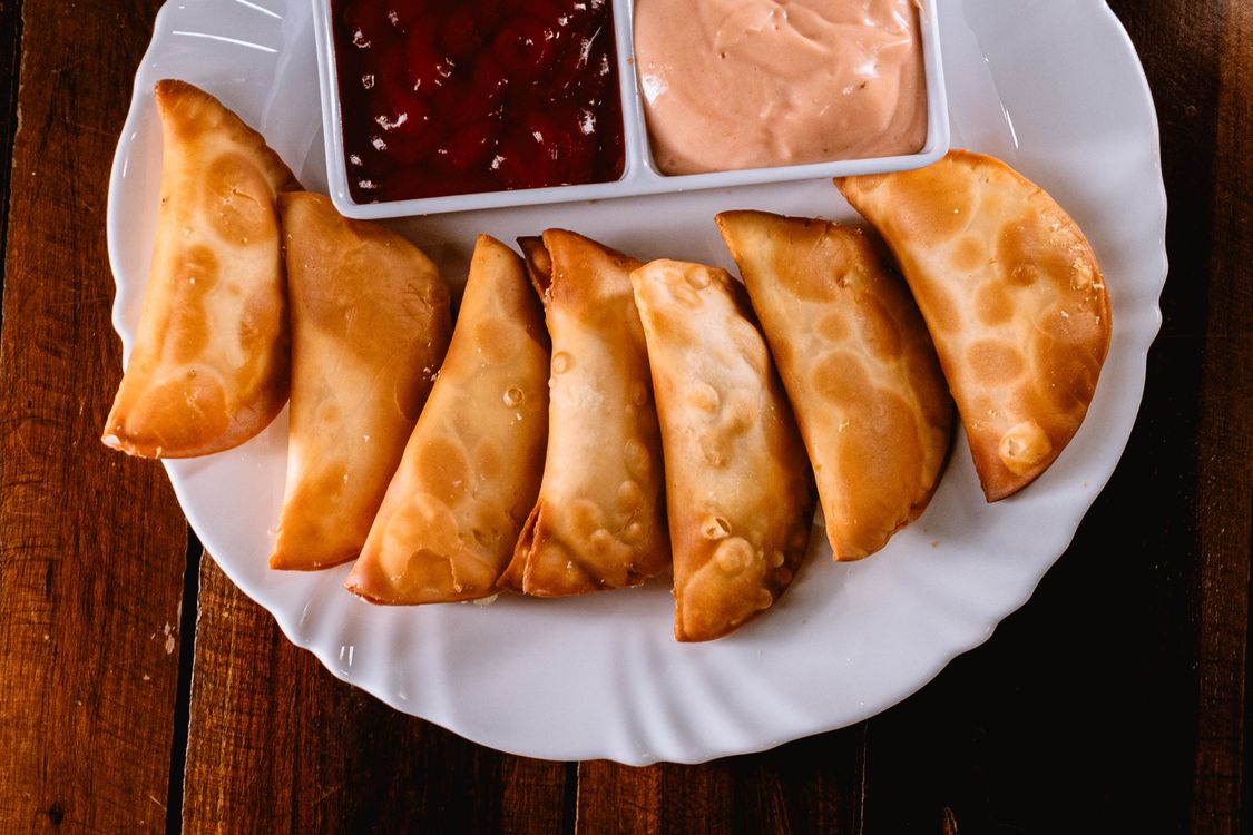 Empanadas venezolanas doradas servidas con salsas en un plato blanco