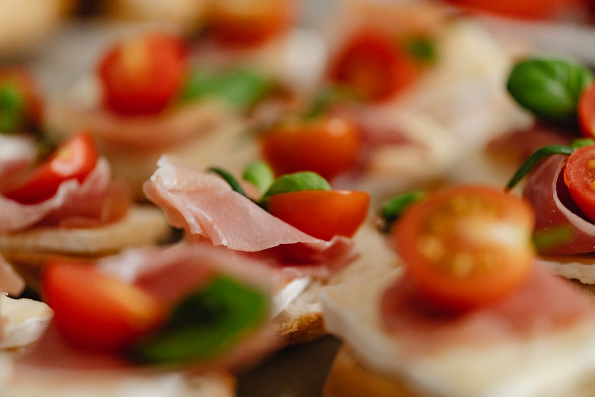 Canapés de pan tostado con jamón y tomate, listos como pasapalo
