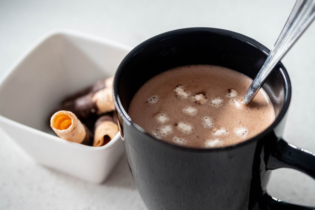 Chocolate caliente en taza negra junto a galletas