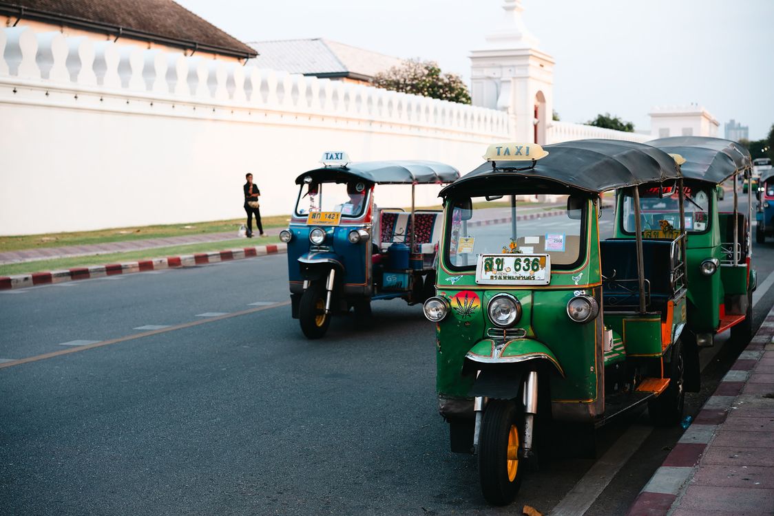 Colorful green and blue tuk-tuks parked on a Bangkok street, an everyday scene where quick translation helps travelers get around