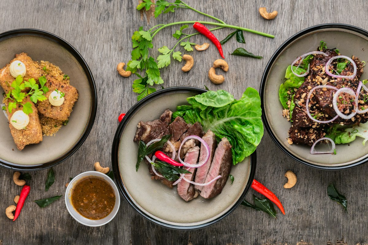 Colorful spread of Thai dishes including curries and stir-fries on a table
