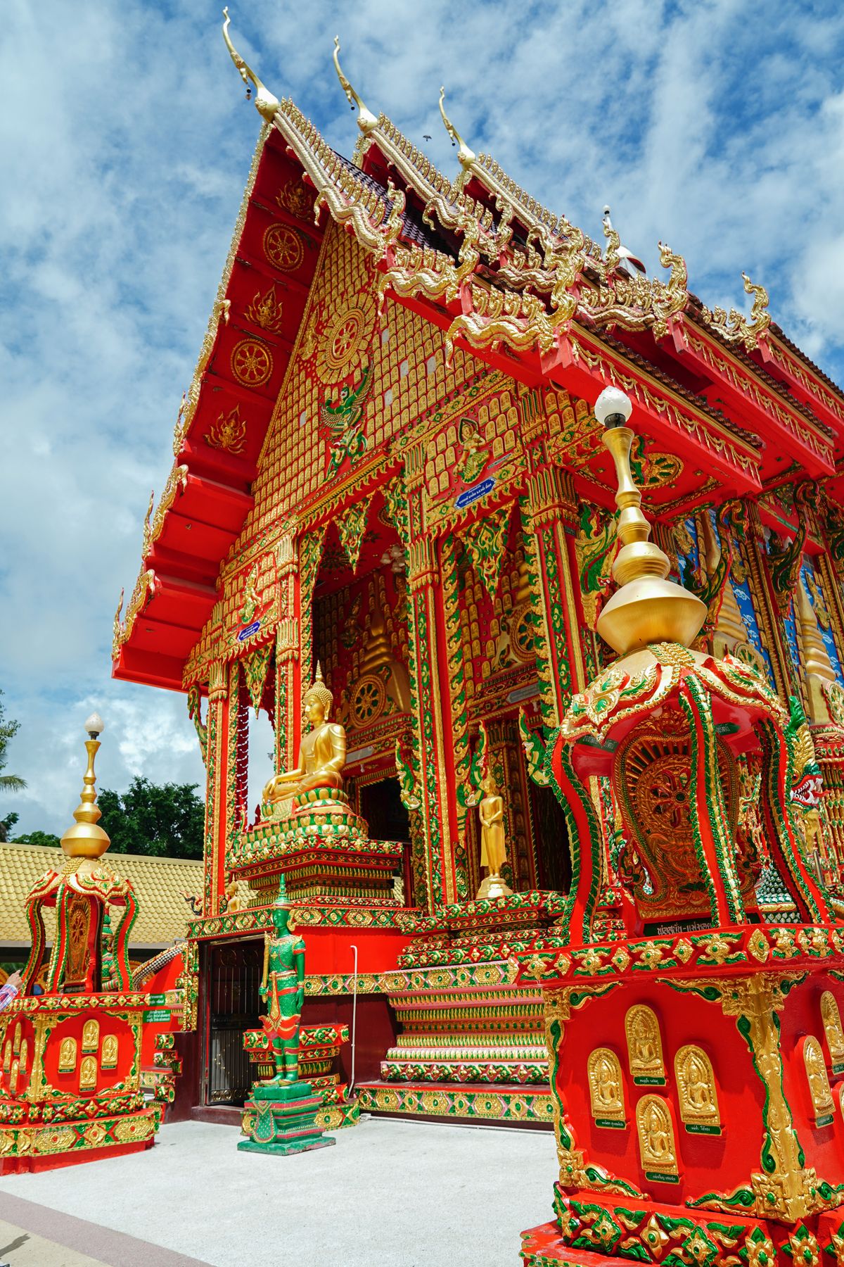 Ornate gold and red Thai Buddhist temple roof with traditional spires against blue sky