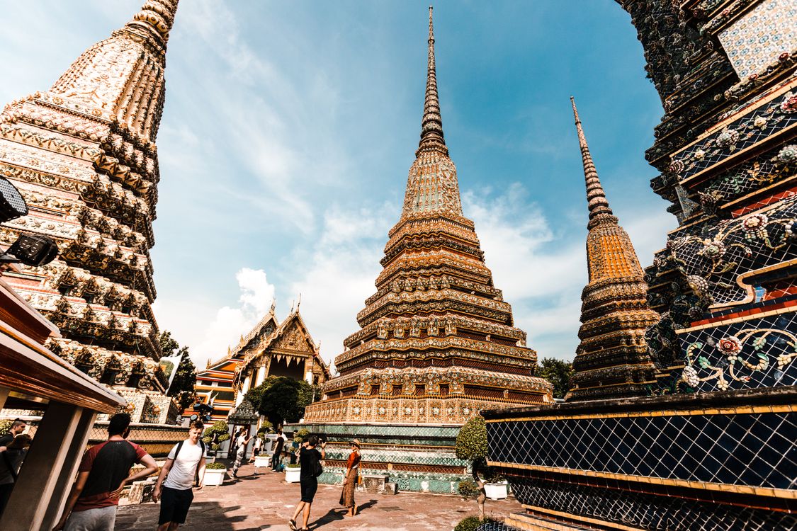 Golden pagodas of Wat Pho temple under a clear sky in Bangkok, Thailand