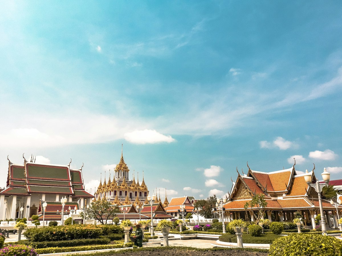 Golden spires of a traditional Thai Buddhist temple against a bright sky