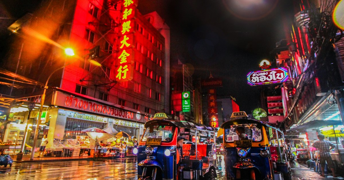 Vendors and travelers at a crowded Bangkok street market, where checking prices helps avoid common scams.