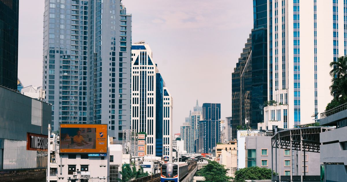 BTS Skytrain passing through Bangkok skyscrapers on a clear day