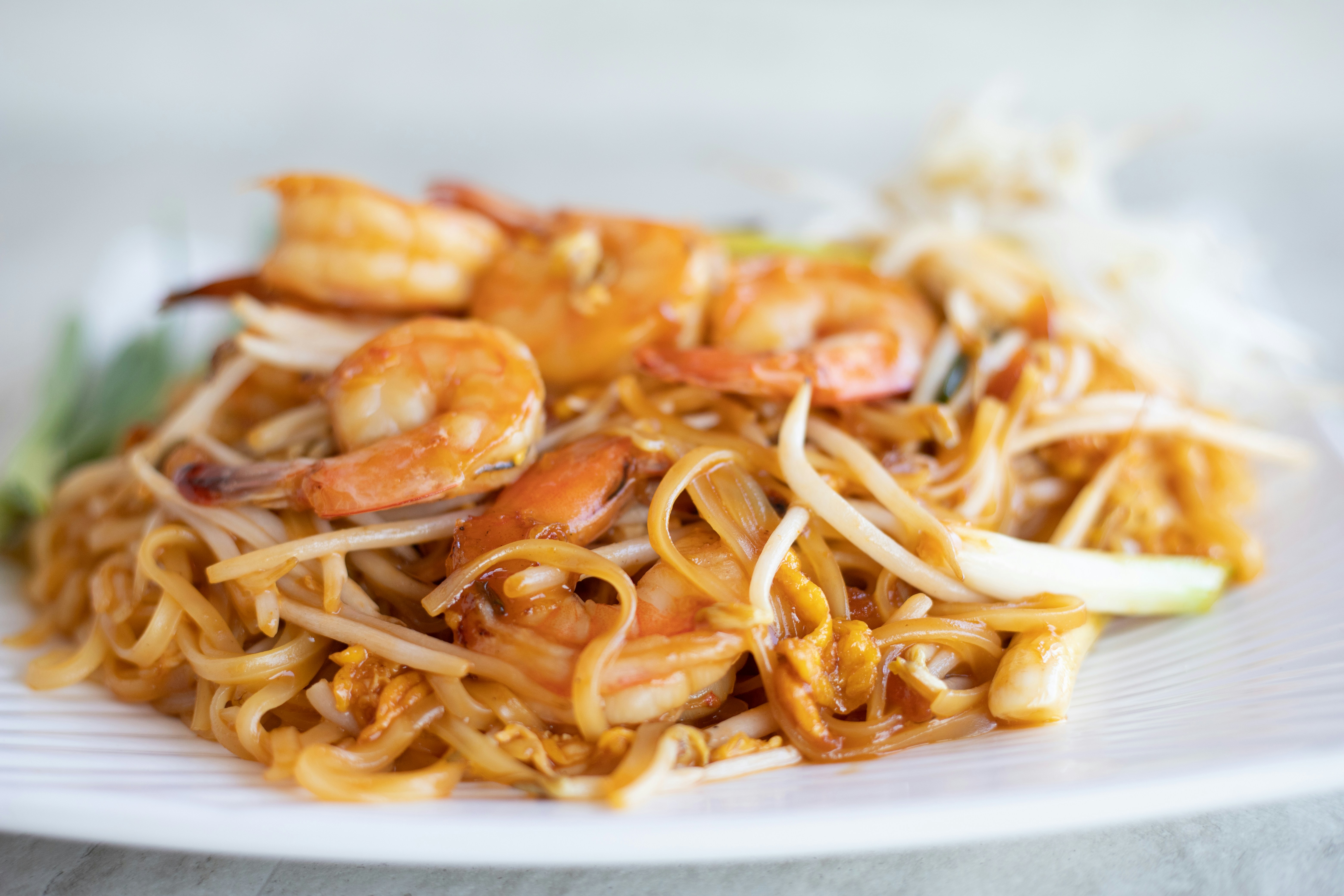 A plate of freshly cooked pad thai with rice noodles, shrimp, peanuts, and lime