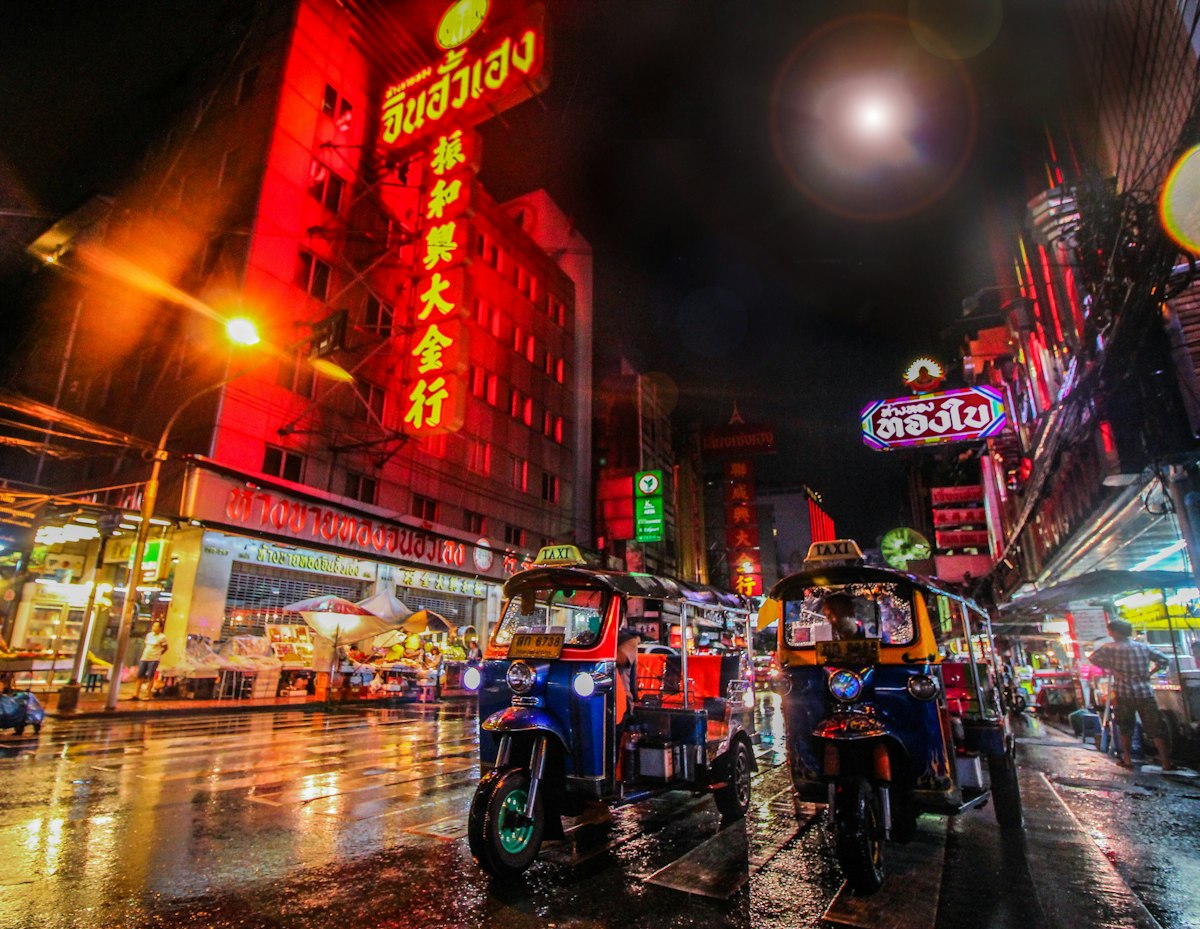 Busy Bangkok street at night with neon signs and traffic