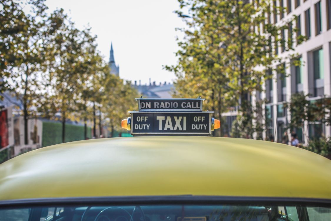 Taxi amarillo con señal iluminada en una calle urbana