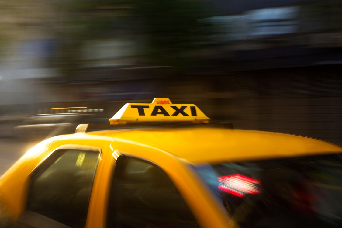 Taxi amarillo en movimiento captado con efecto de barrido en una calle de ciudad