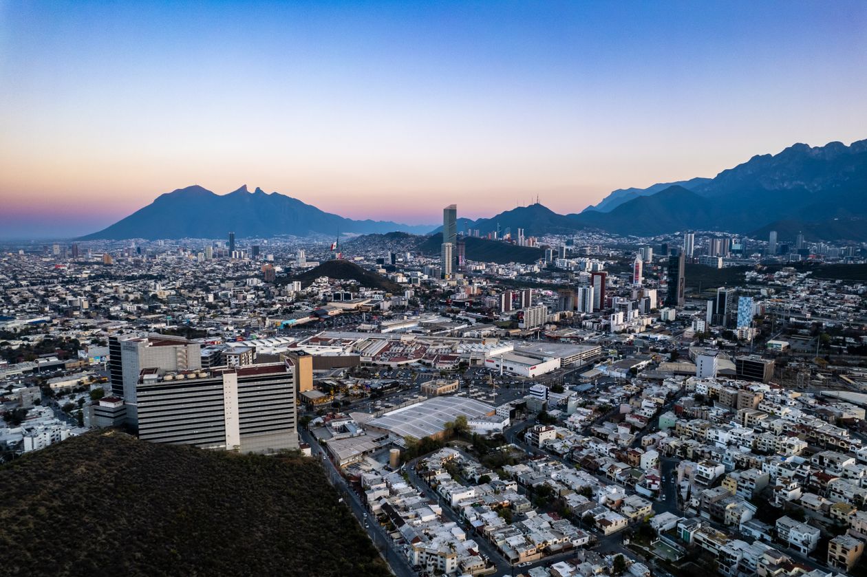 Vista del skyline de Monterrey con edificios altos y montañas bajo cielo azul