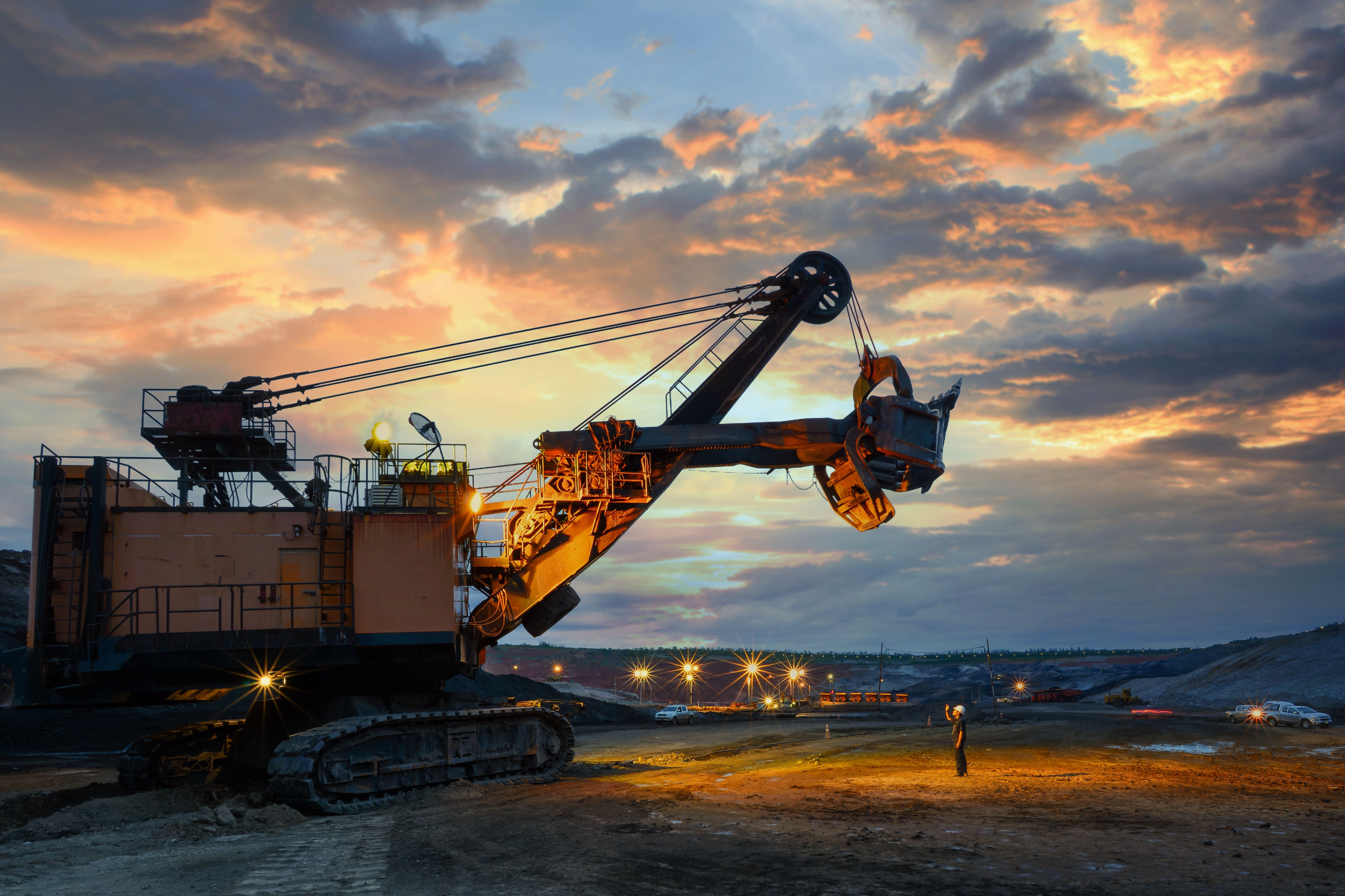 Excavadora amarilla de maquinaria pesada operando en sitio al atardecer