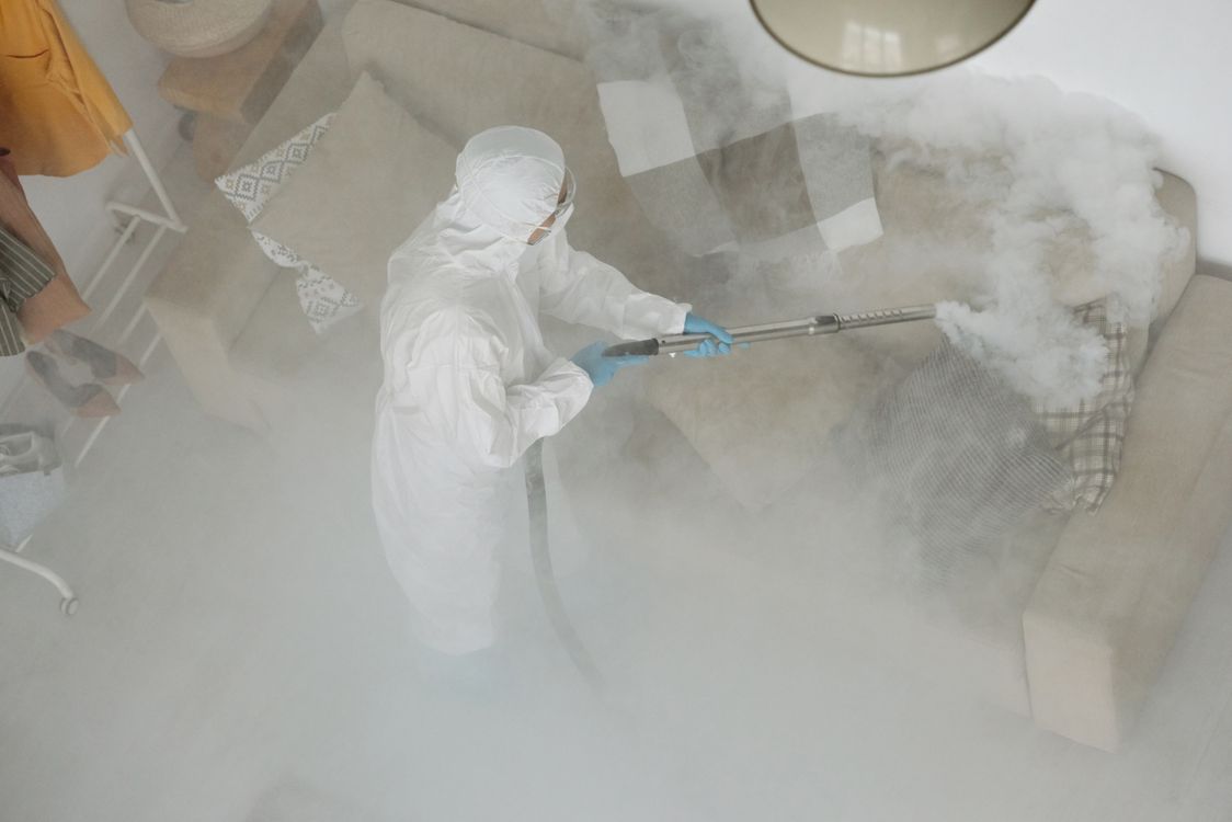 Técnico de fumigación en traje protector aplicando tratamiento en una sala residencial