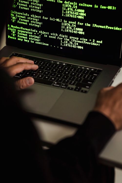 Primer plano de manos escribiendo código en una laptop durante un incidente de ciberseguridad