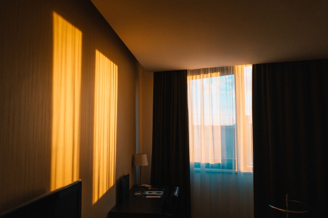 Contemporary hotel room in warm morning light filtering through sheer curtains