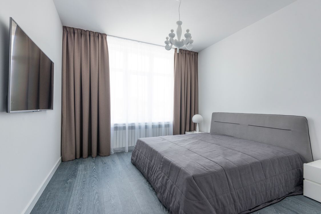 Minimalist room with elegant drapes framing a bright window, showing controlled natural light