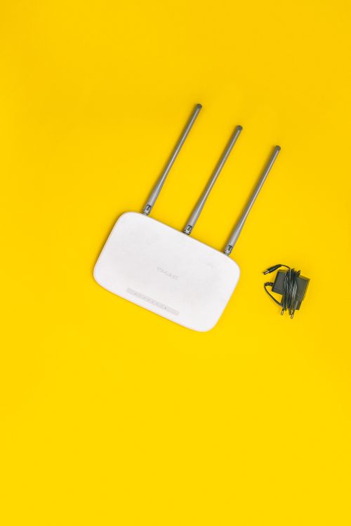 Router inalámbrico blanco con antenas sobre fondo amarillo