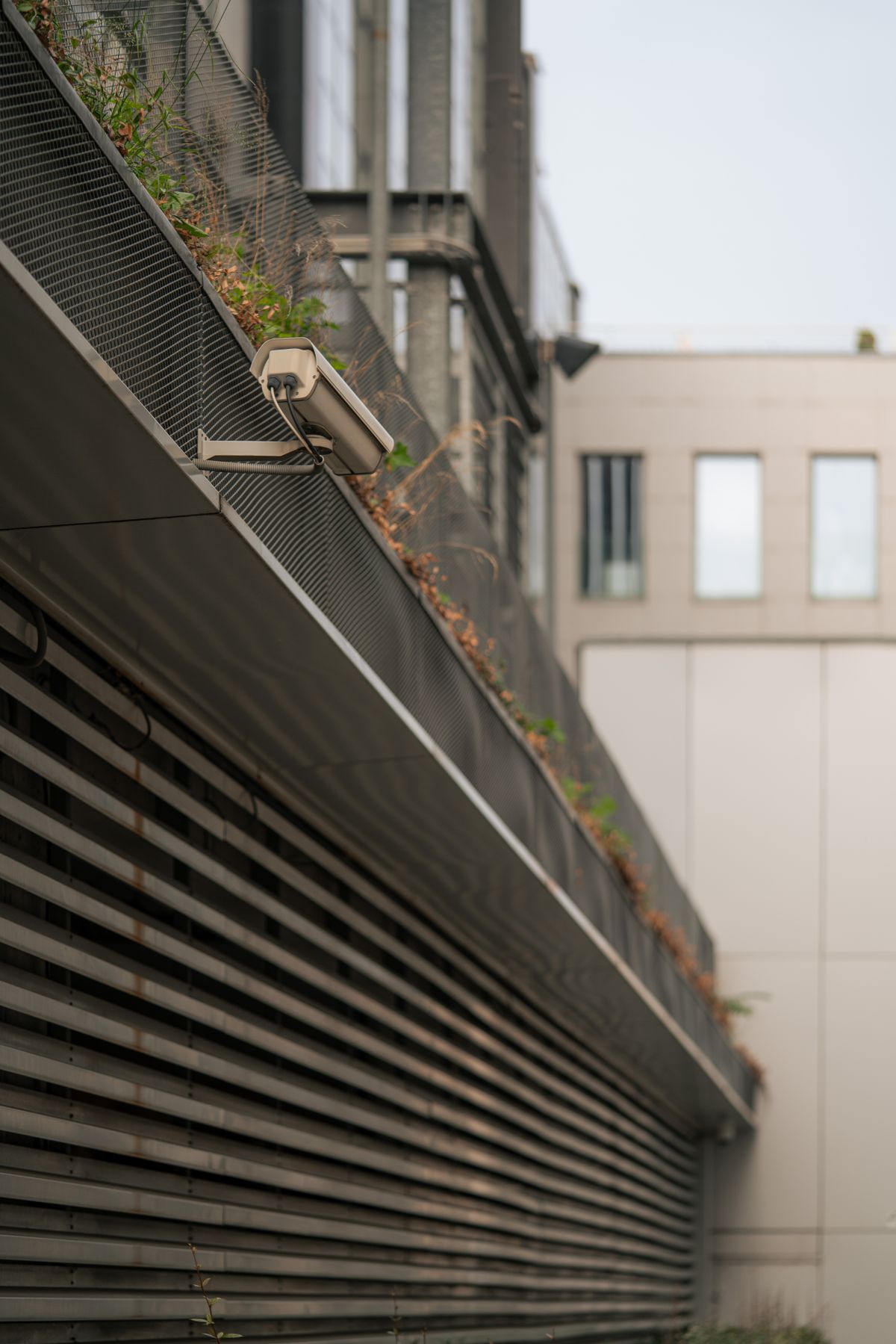 Cámara CCTV blanca instalada en pared gris de edificio residencial