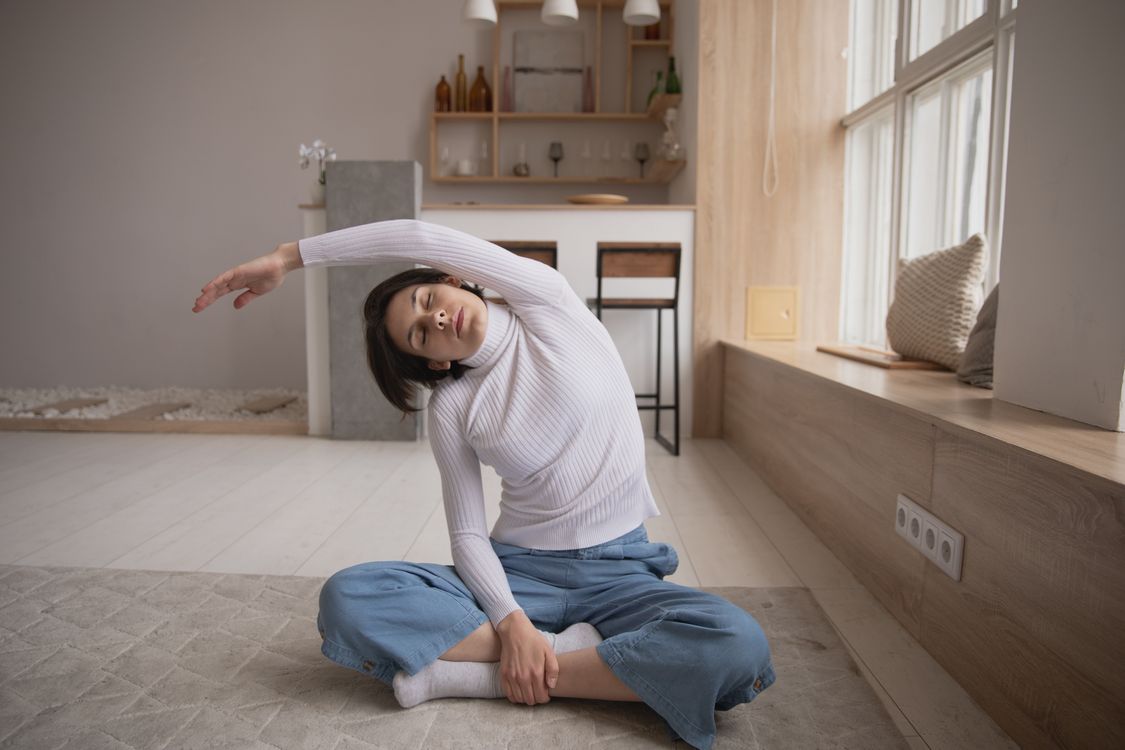 Mujer haciendo estiramiento lateral suave en ambiente interior