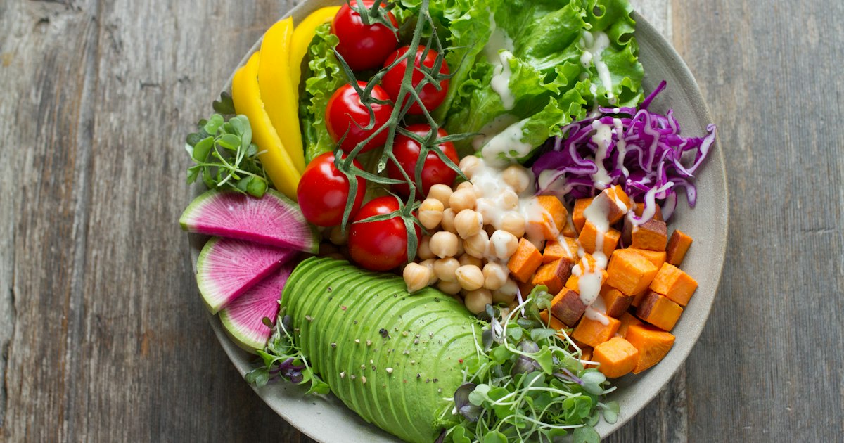 Variedad de verduras, frutas y alimentos frescos ordenados sobre una superficie clara