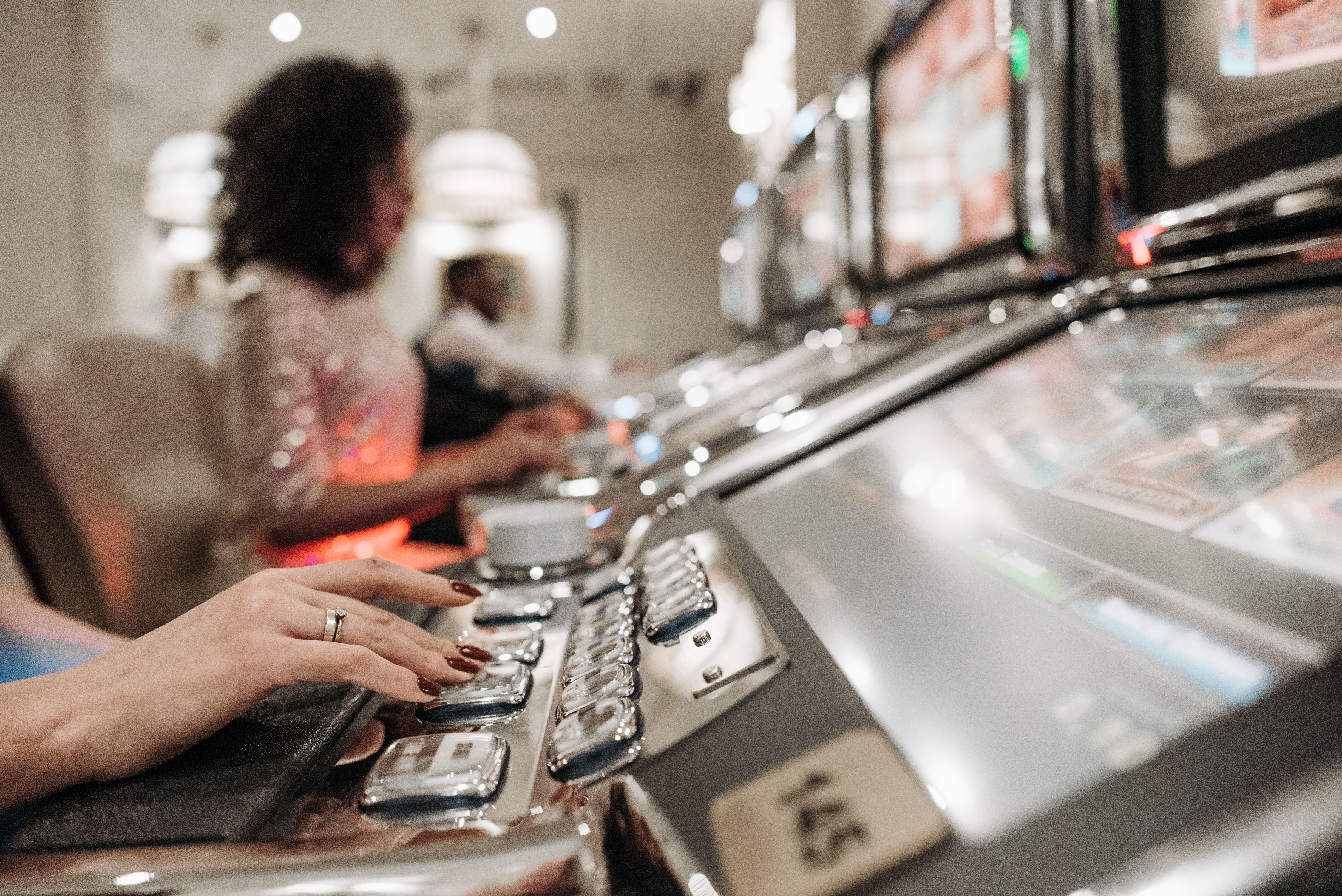 Pemain menekan tombol pada mesin slot di kasino