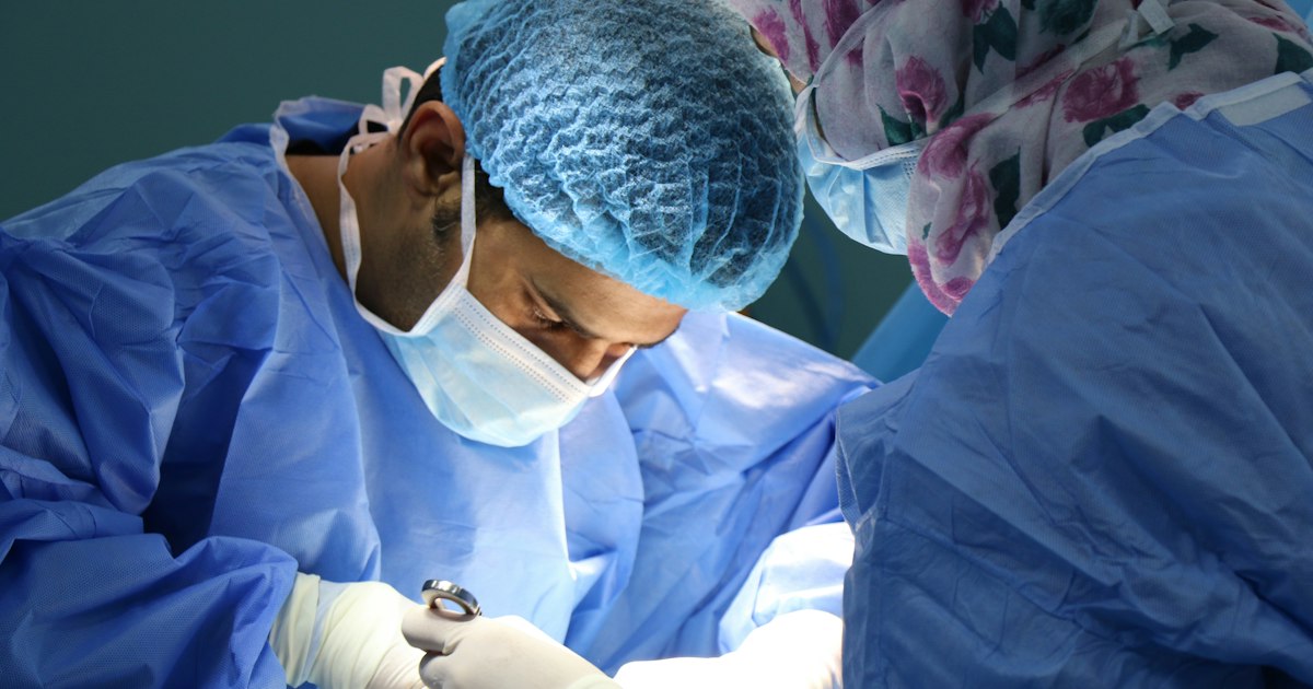 Cirujano con bata y guantes quirúrgicos preparándose para una operación en quirófano moderno