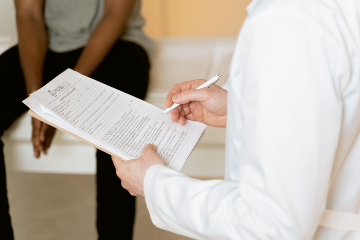 Manos de un profesional de la salud revisando documentos médicos durante una consulta