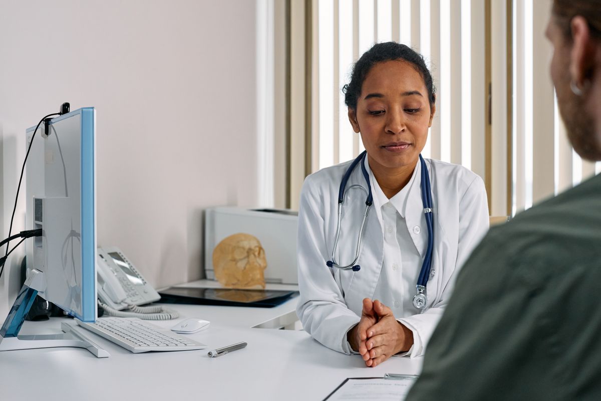 Médico con estetoscopio conversando con un paciente durante una consulta médica