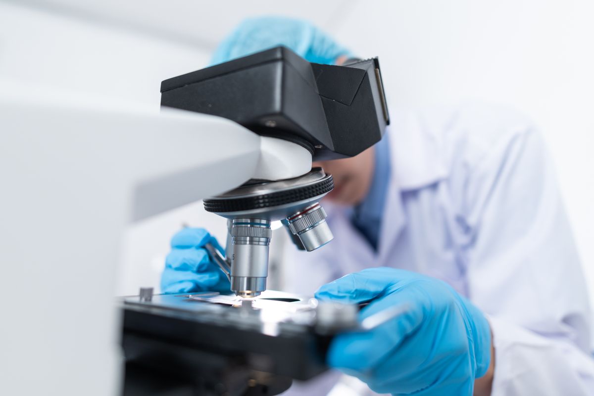 Cientista usando microscópio de laboratório para análise de amostras