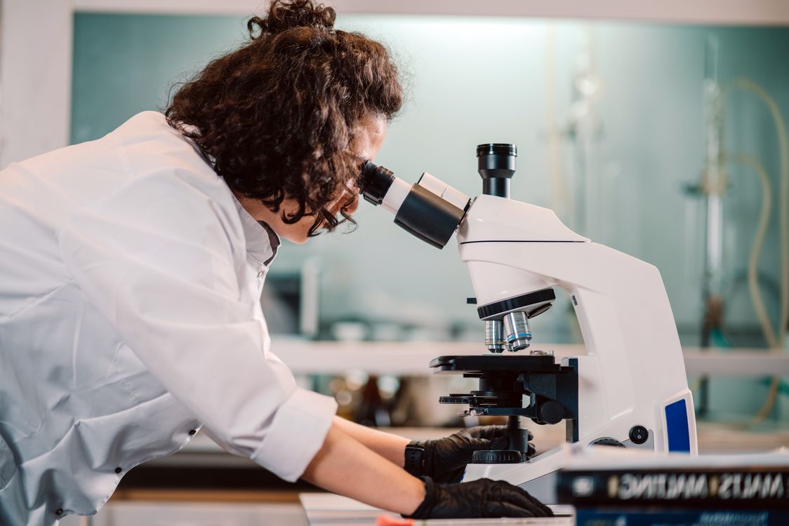 Cientista observando amostras através de um microscópio de laboratório em ambiente de pesquisa