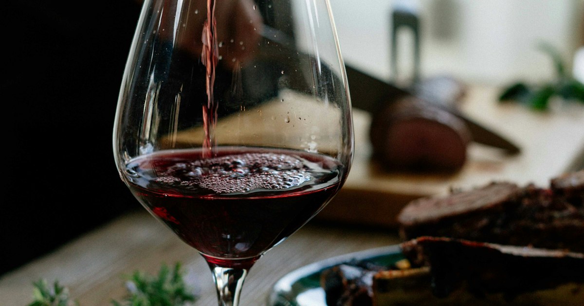 Vino tinto siendo servido en una copa de cristal