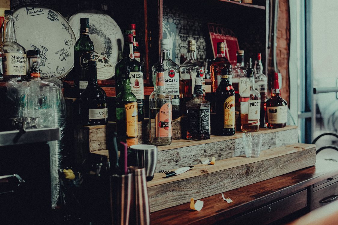 Botellas de licor variado en estantería de bar iluminada