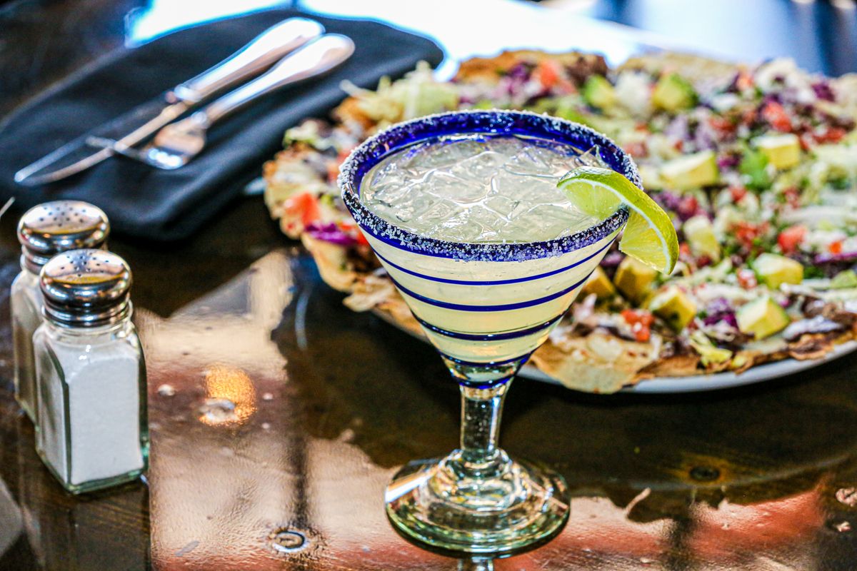 Copa de margarita con borde de sal y rodaja de limón sobre una mesa
