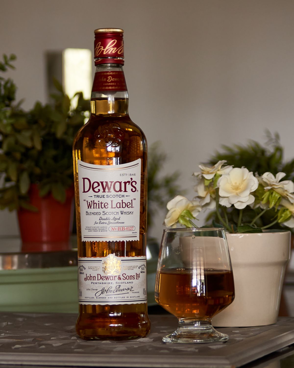 Botella de whisky junto a un vaso servido sobre una mesa elegante
