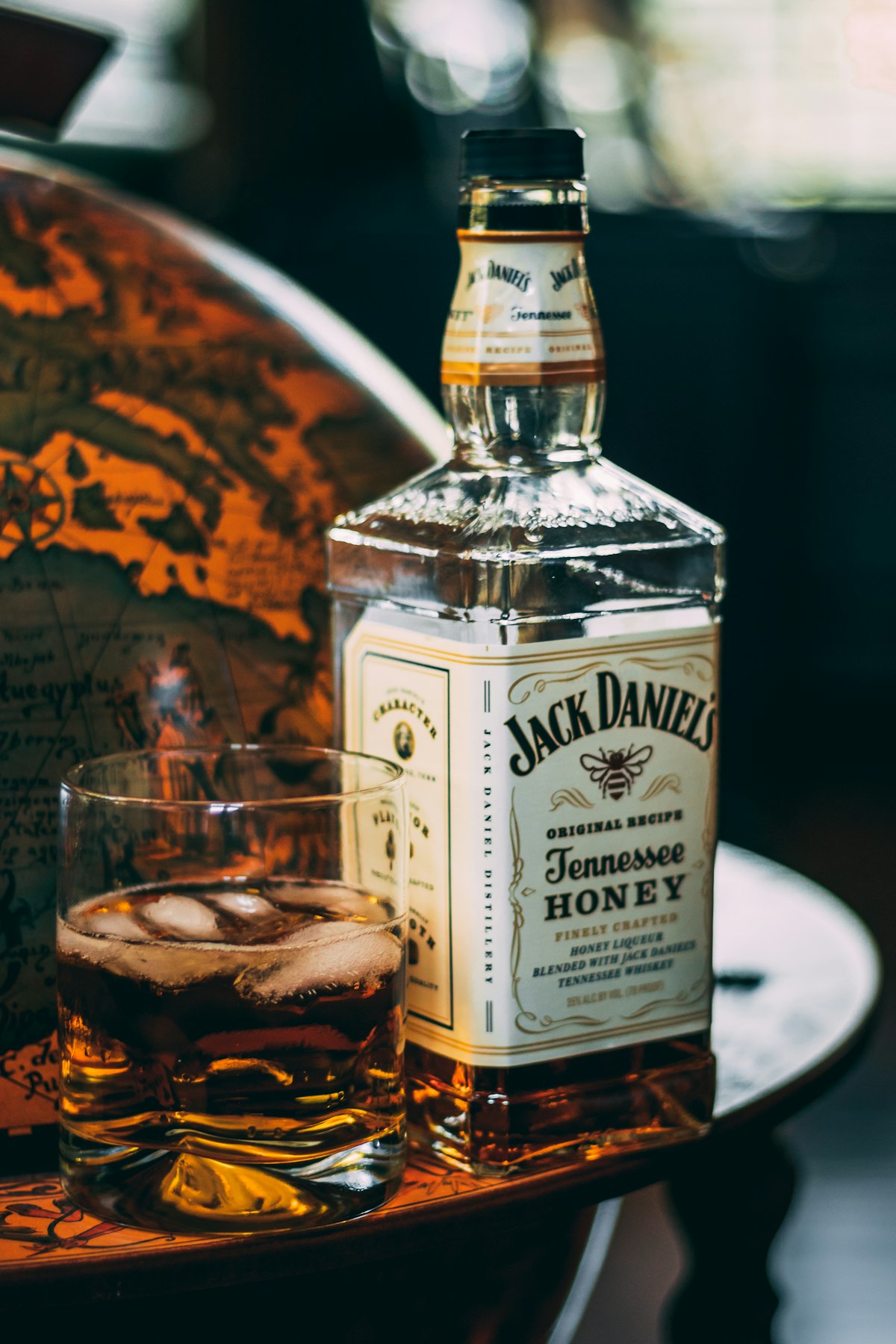 Vaso de whisky con esfera de hielo sobre madera